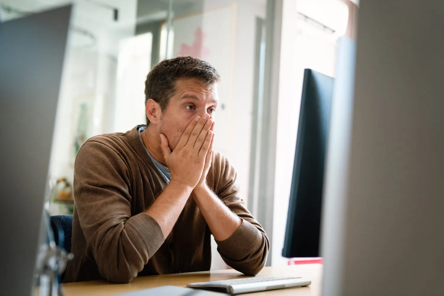 A worried man covering his face at his desk